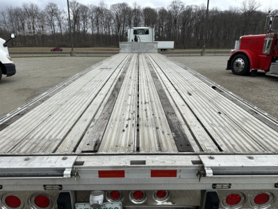 Flatbed trailer deck of a 2019 Reitnouer Big Bubba showing aluminum planks, rear lights, and towing clearance.
