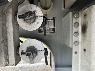Trailer deck feature showing two circular landing gear or suspension access covers labeled UP and DOWN with levers, metal frame with rivets and bolts.