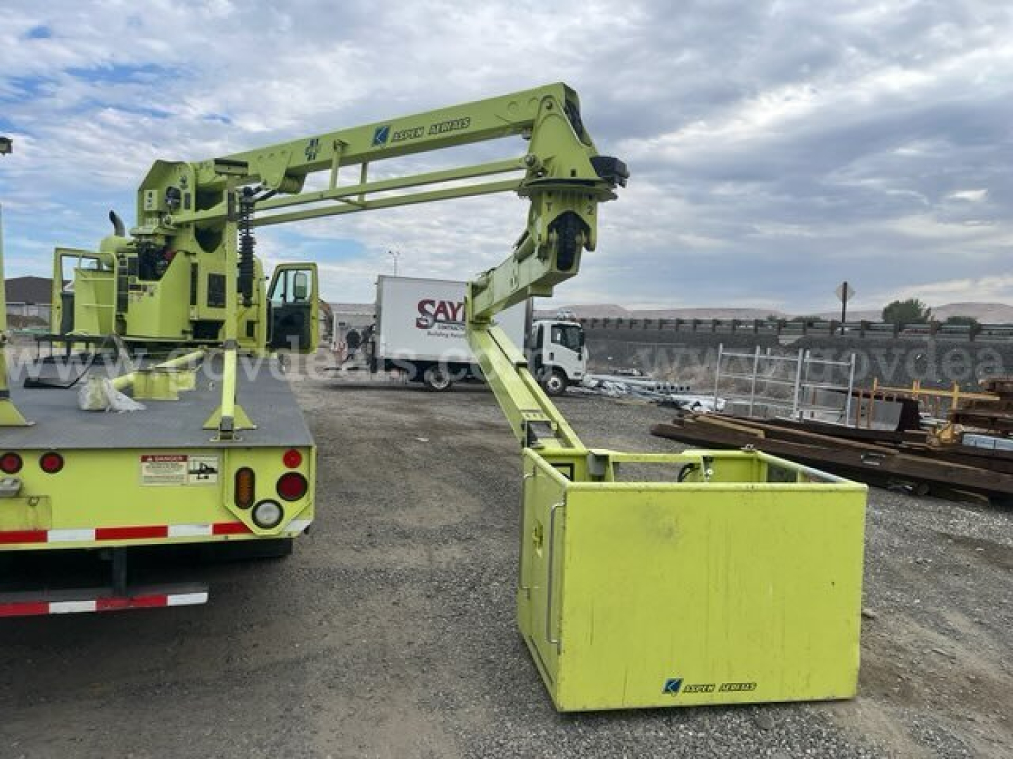 Truck-mounted boom lift on a lime-green truck chassis with an extended arm and a yellow storage box at the end, 2005 International 7600 bucket truck.
