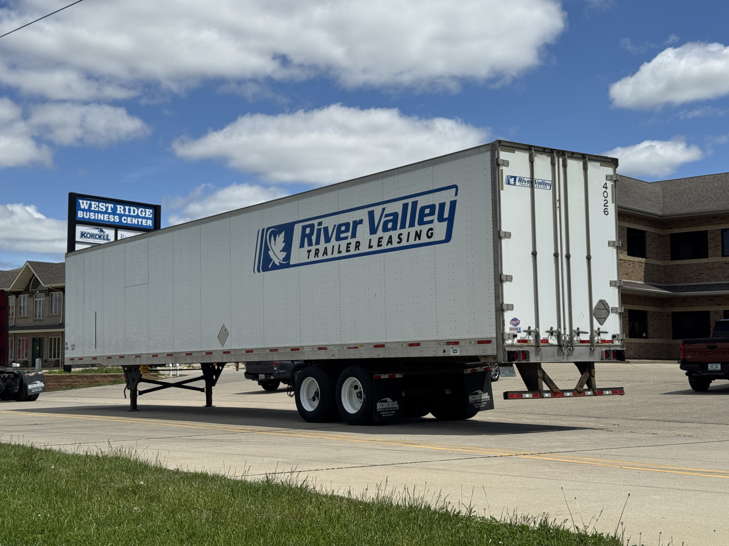 Trailer side view showing a River Valley Trailer Leasing logo on a white utility 4000D-X trailer with dual axles parked on a street.