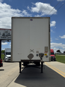 Rear view of a 2014 Utility trailer 4000D-X showing a plain white back door with warning decals and lighting components.