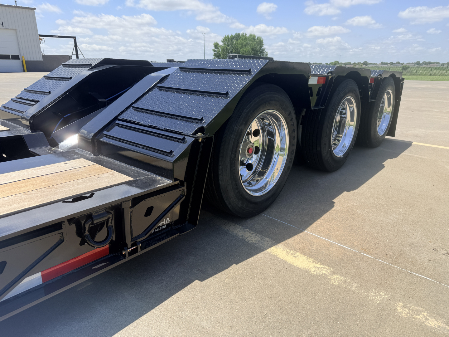 Alpha A110HDG-SF-18" LDH lowboy trailer showing dual rear axles with chrome wheels and textured fenders.