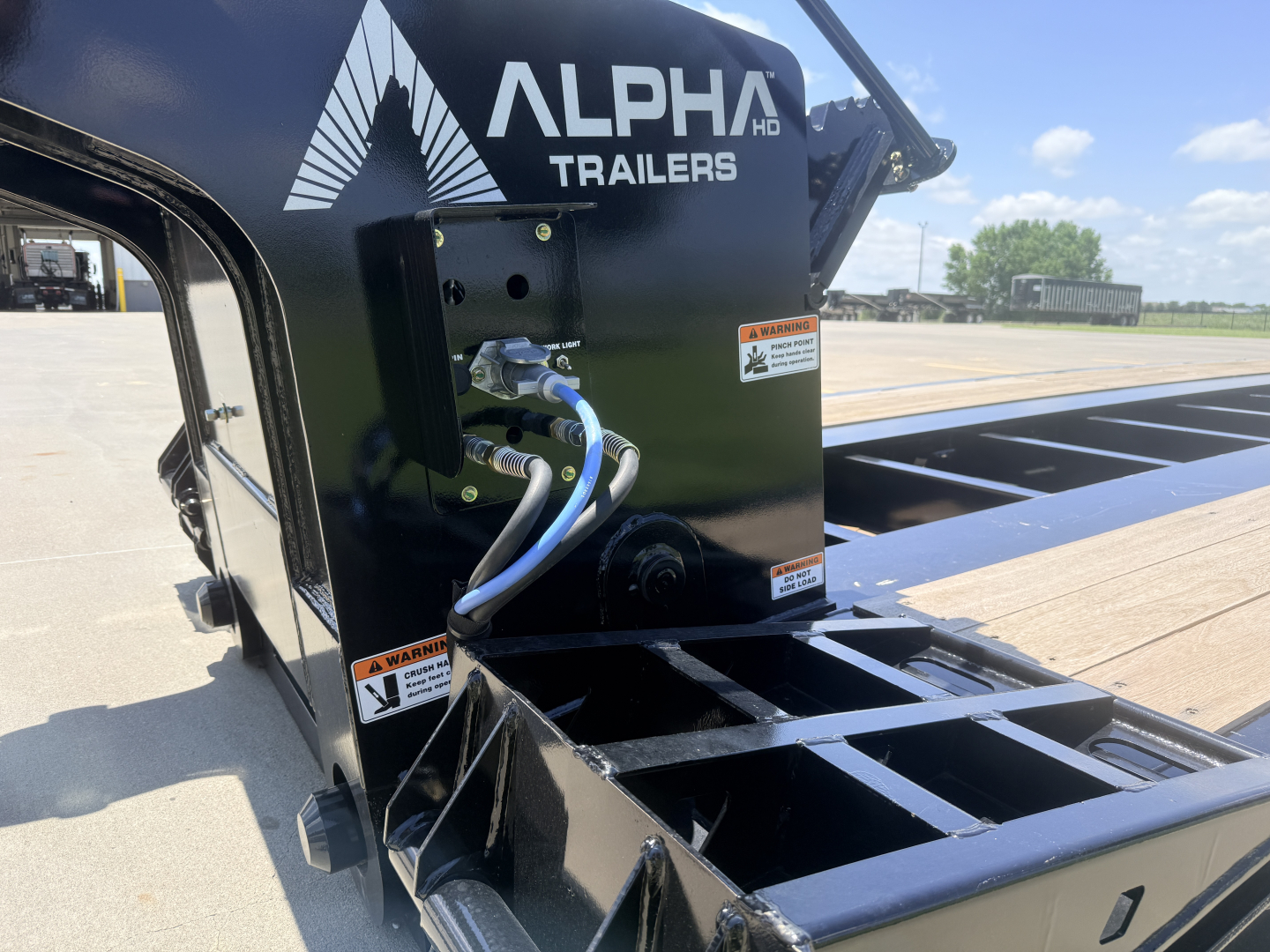 Alpha Trailers A110HDG-SF 18 inch LDH lowboy trailer with hydraulic attachment and blue hoses, Alpha Trailers logo on black steel housing, flatbed deck visible