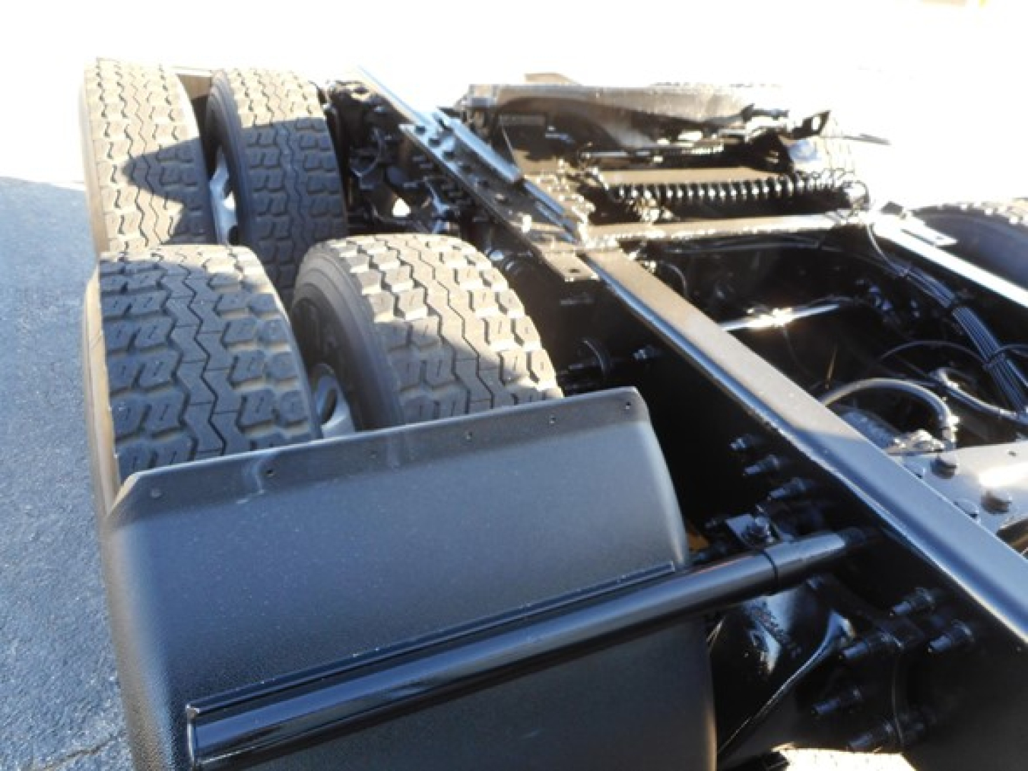 Freightliner Cascadia truck chassis showing dual rear axles and suspension components with tires and frame visible.