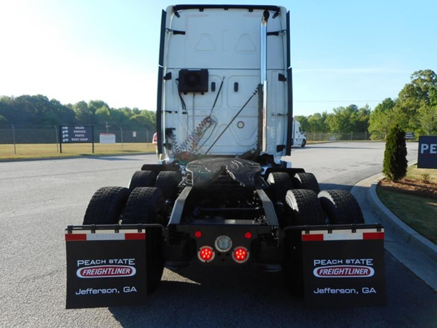 Truck rear view showing fifth wheel and dual rear axles of a Freightliner Cascadia 126 tractor in a dealership lot. Mud flaps read Peach State Freightliner, Jefferson, GA.