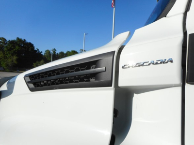 Freightliner Cascadia 126 truck corner showing Cascadia badge on white cab and front grille.