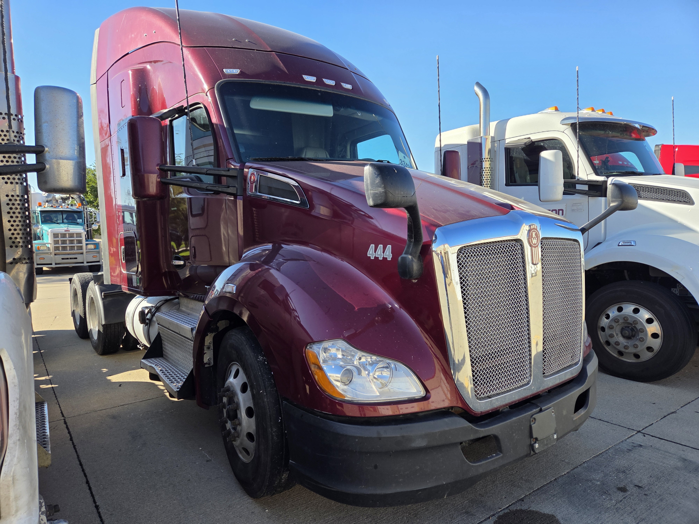 Kenworth T680 tractor in burgundy showing front grille, headlights, and lengthened sleeper cab. Vehicle details not readable.