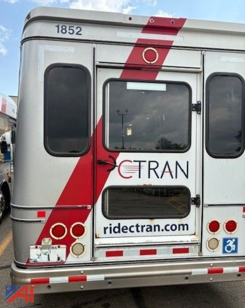 Rear view of a used 2018 Ford E450 transport bus showing the back doors, window, and branding 'ride tran' with the route site. Vehicle number 1852 visible at top left.