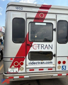 Rear view of a used 2018 Ford E450 transport bus showing the back doors, window, and branding 'ride tran' with the route site. Vehicle number 1852 visible at top left.