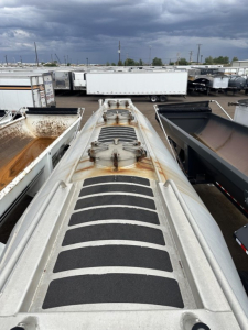 Trailer top view showing matte anti-slip steps and access hatches on a 2019 Mac 1050 Cu Ft Pneumatic trailer in a lot of similar trailers.