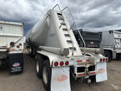 Mac 1050 cu ft pneumatic trailer showing rear view with ladder, safety rails, and three-axle setup; visible branding and mud flaps.