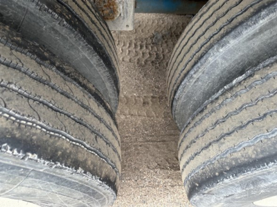 Dual rear pneumatic trailer tires mounted on a Mac 1050 cu ft pneumatic trailer showing tread wear and dirt between wheels.