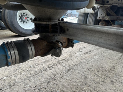 Trailer underside with pneumatic system fittings and connectors; hose clamp and suspension components visible.