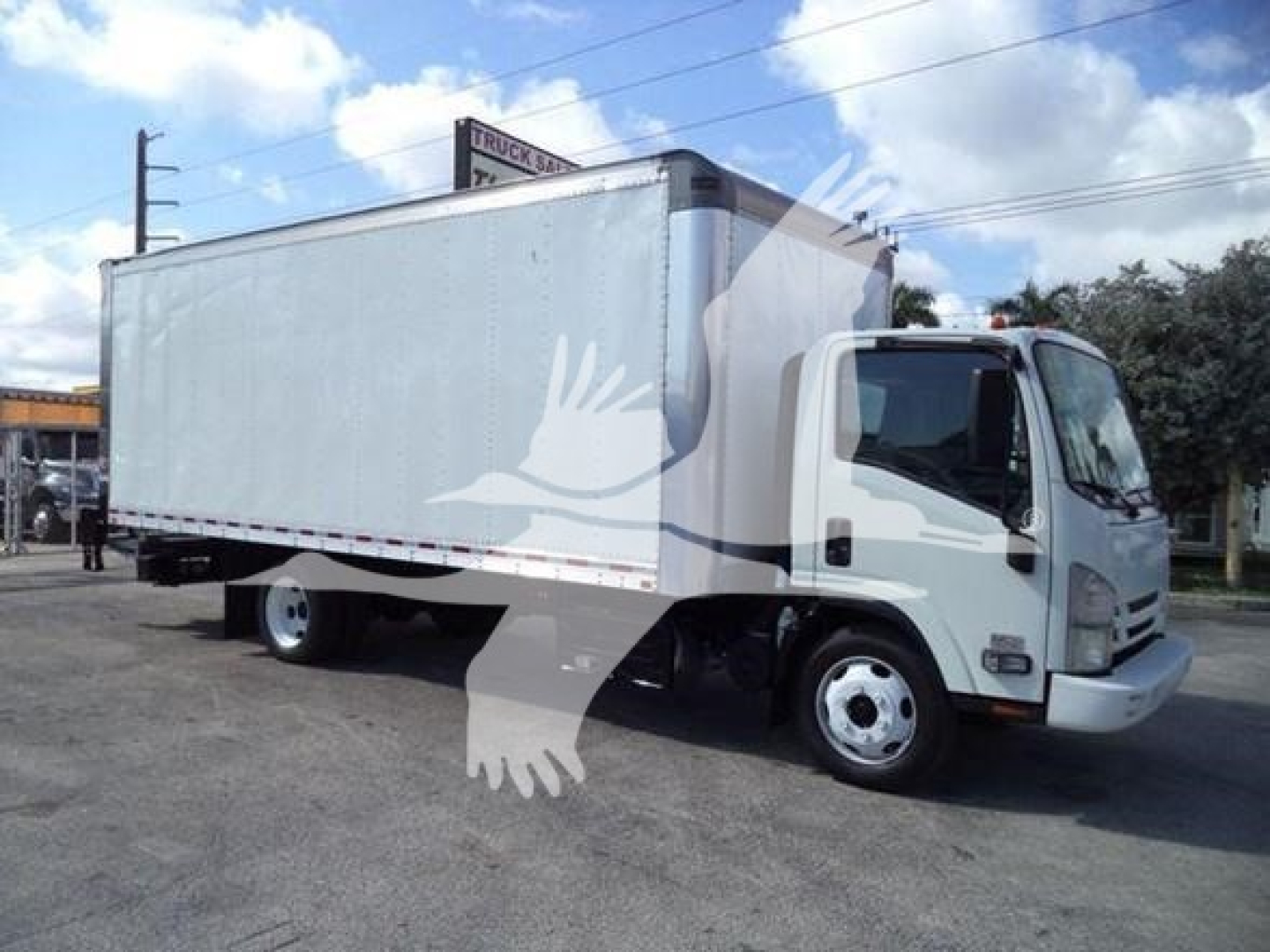 Isuzu NPR-style box truck with a large cargo box on a low cab, front wheels visible, side view showing box body.