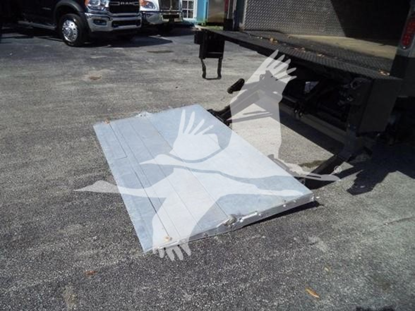 Truck bed with a metal platform/step near a Isuzu NRR box truck rear; loading dock area visible.