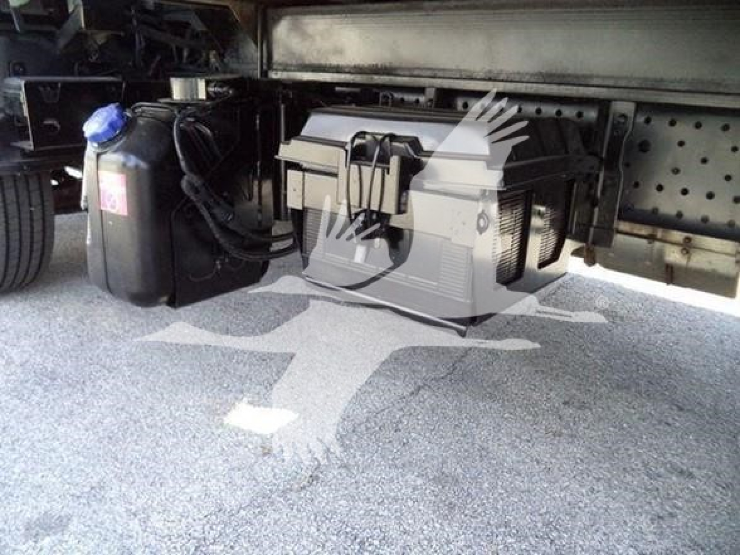 Isuzu NPRR undercarriage showing tool box and auxiliary reservoir mounted to frame with hoses and wiring nearby.