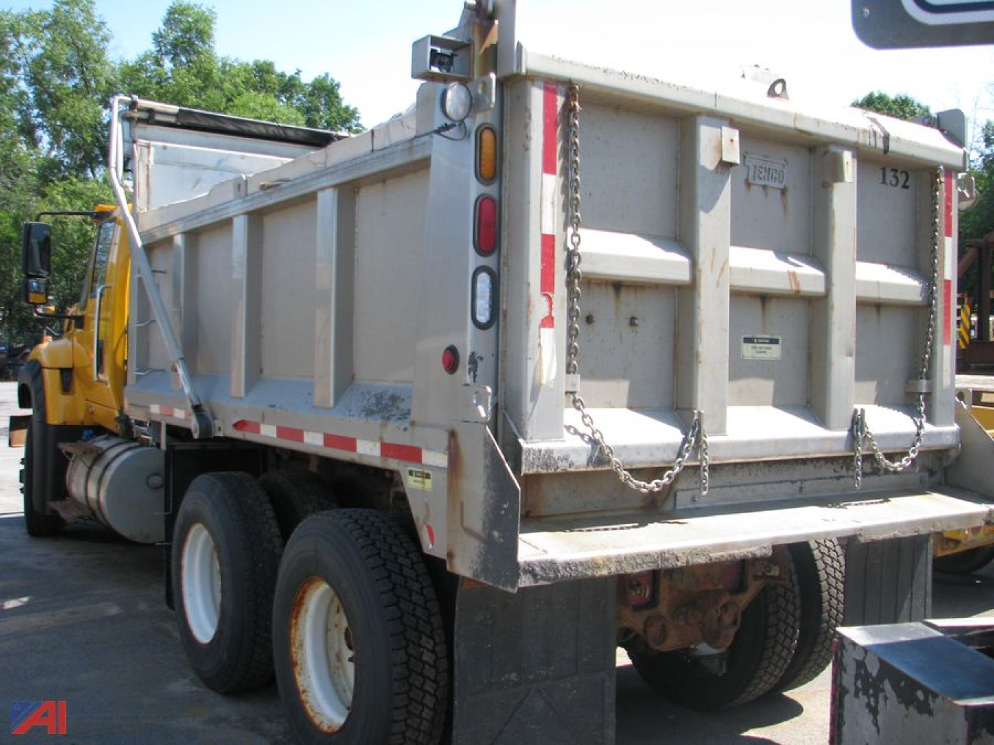 Dump truck rear view showing dump bed on International WorkStar 7600 with dual rear wheels and chains on tailgate.