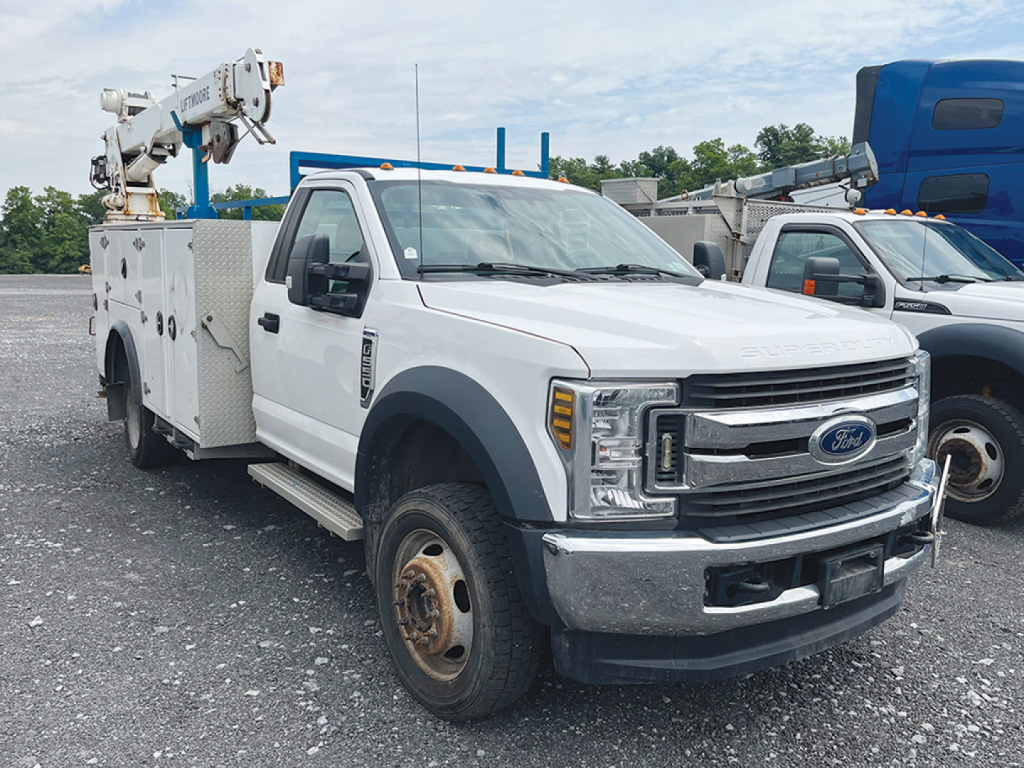Ford F-550 XL Super Duty utility truck with bucket lift on service body, front view showing grille, headlights, and utility compartments.