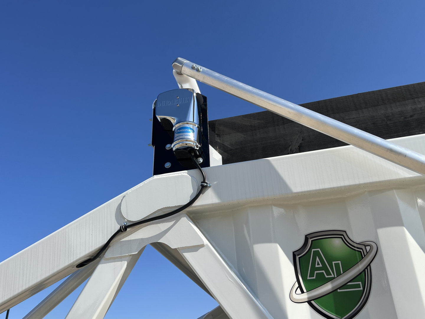 Trailer hitch mechanism and frame of Armor Lite SBD42 tri-axle air ride trailer showing aluminum body, bolt-on bracket, and a hydraulic or pneumatic actuator.