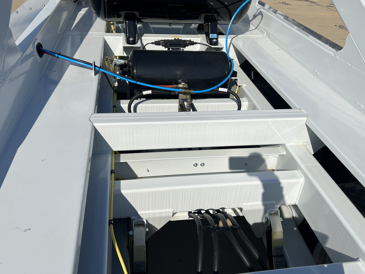 Front view of Armor Lite SBD42 tri-axle air ride trailer chassis showing hydraulic lines, battery box, and wiring harness.