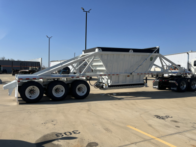 Wheel-end view of a white Armor Lite SBD42 tri-axle air ride trailer with a dump bed, exposed chassis, and multiple axles.