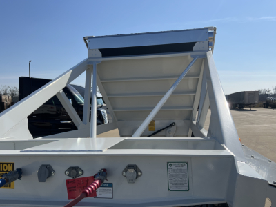 Dump trailer rear view showing skeleton structure and air ride components, white-painted metal frame and warning labels.