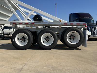 Triple-axle trailer wheel assembly with air ride components and silver frame, side view showing three tires and reflectors.