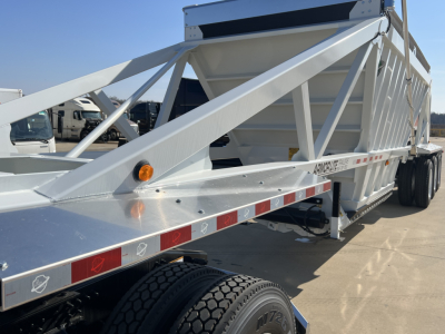Tri-axle dump trailer frame with air ride suspension and reflective tape along side, Armor Lite SBD42 branding visible on white painted steel.