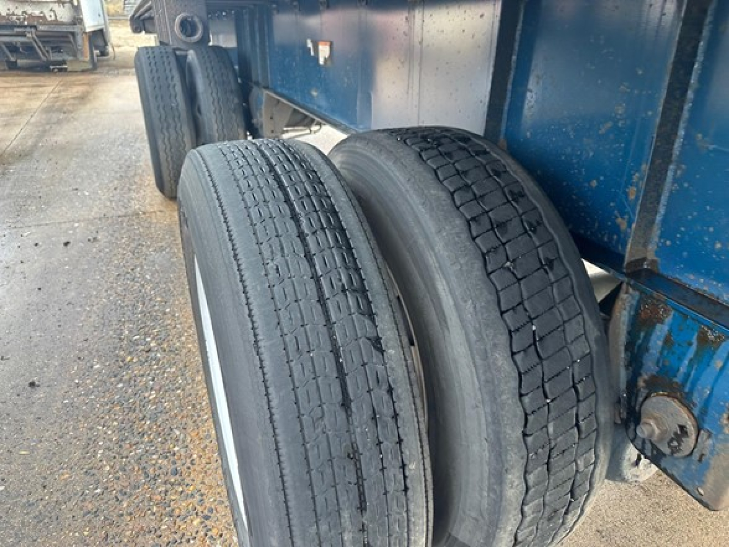 Two trailer tires mounted on the rear axle of a blue Great Dane Freedom LT trailer; tread detail visible and undercarriage with suspension and frame components.