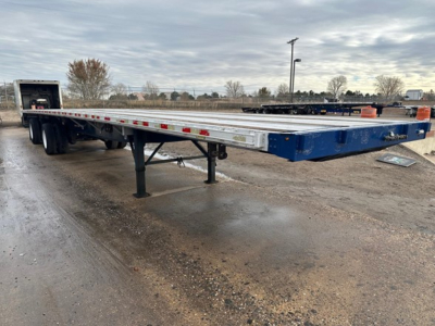 Flatbed trailer by Great Dane with blue front and aluminum deck, extended, no cab visible; shows gooseneck area and support legs, trailer appears on gravel lot.