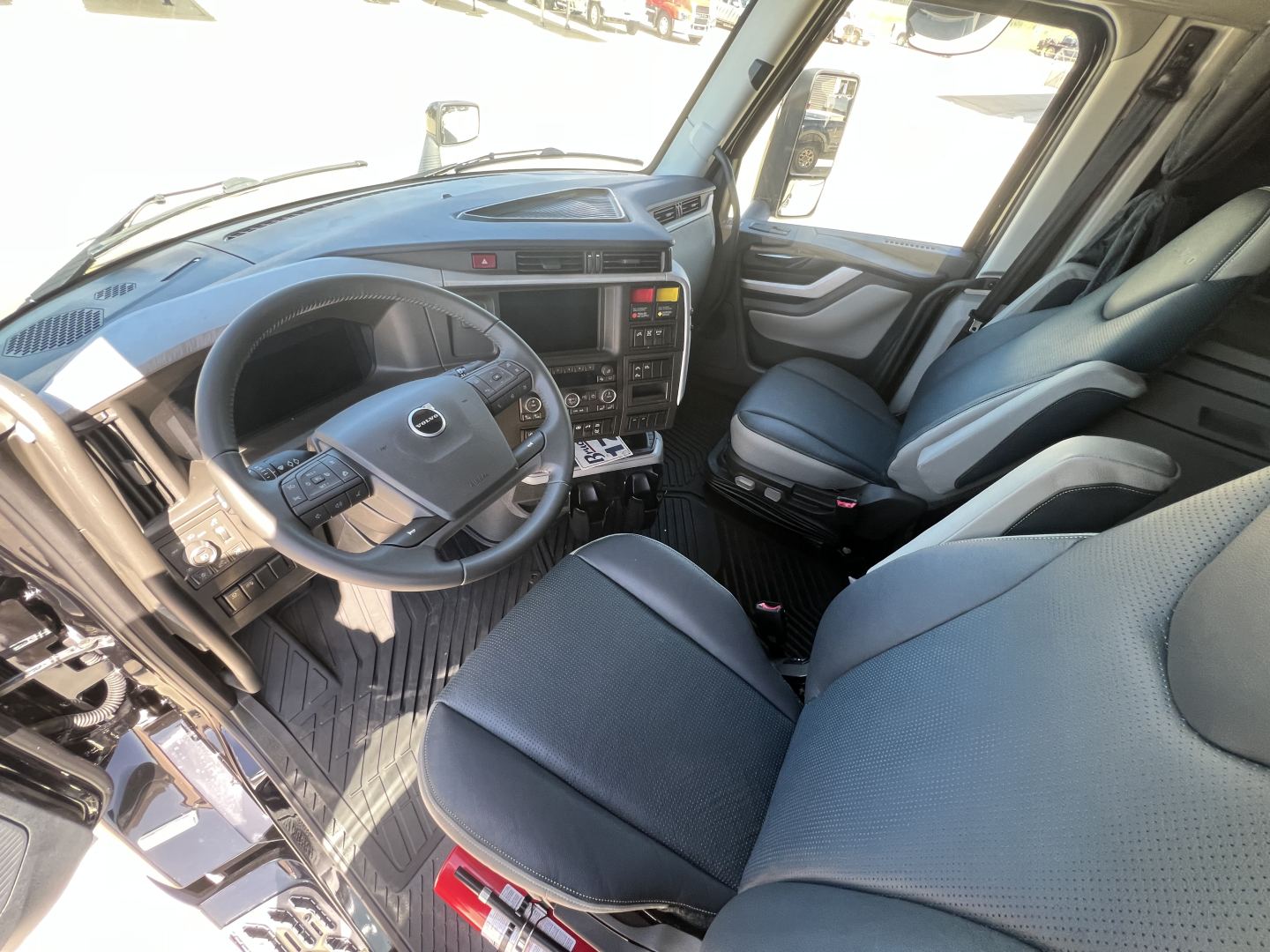 Volvo VNL64T840 cabin interior showing steering wheel, dashboard, and driver and passenger seats.