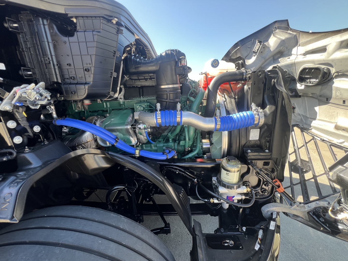 Volvo VNL64T840 engine bay showing green diesel engine with blue silicone hoses and surrounding components.