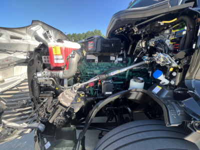 Engine bay of a Volvo VNL64T840 conventional sleeper showing diesel engine, fuel filters, hoses, and electrical components.