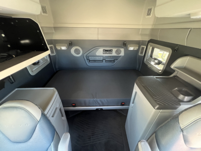 Volvo VNL64T840 sleeper cab interior showing bunk bed platform and cabinet areas with storage shelves and small sink on right.