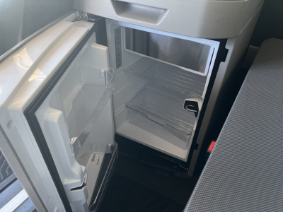 Volvo VNL64T840 interior showing open compact refrigerator/freezer unit and empty lower storage with shelves.