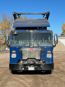 Peterbilt 520 front view showing grille, headlights, bumper, and hood with crane attachment on a blue truck.