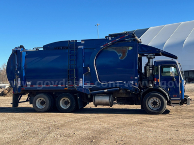 Peterbilt 520 garbage truck in blue, side view with hydraulic arm and rear compactor, stock number 4677-228 visible.