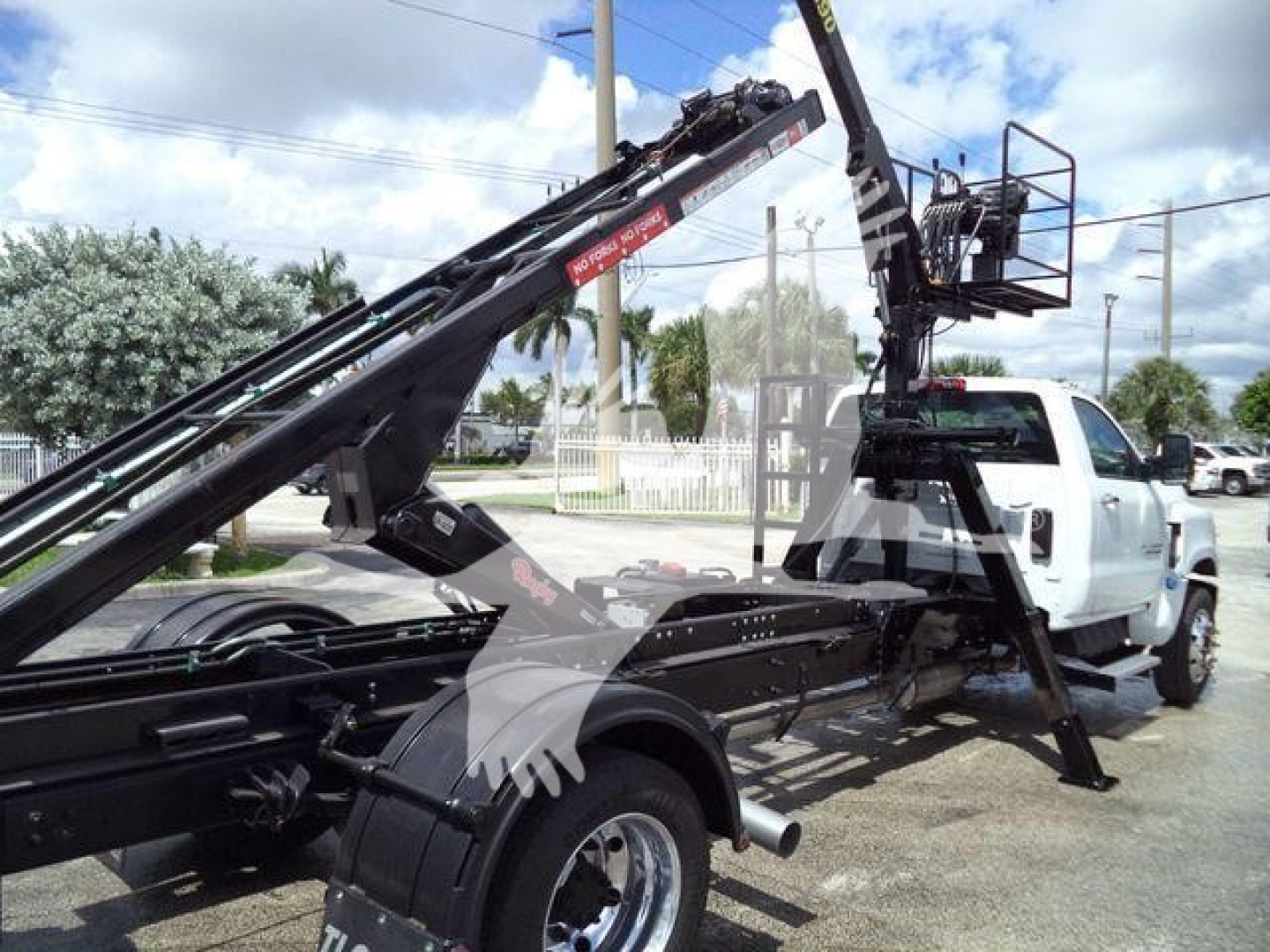 Chevrolet Silverado 6500HD roll-off truck with telescopic crane and platform, side view showing chassis, hydraulic arms, and cab.