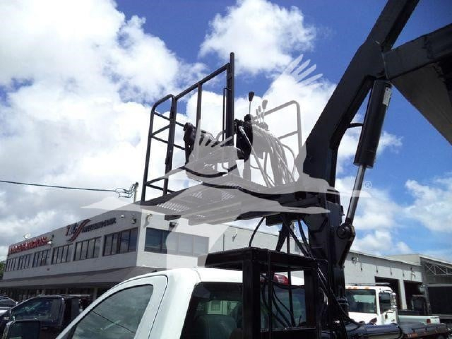 Truck body with a raised crane on a white Chevrolet Silverado 6500HD in a dealership lot.