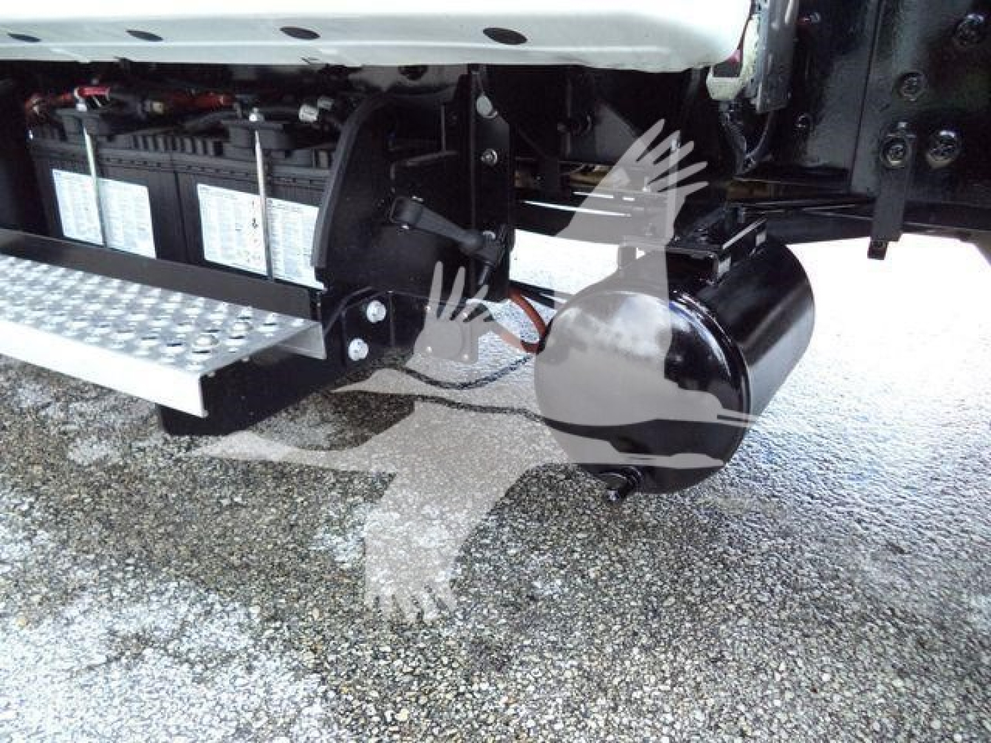 Truck undercarriage showing dual battery/power module, metal steps, and a large round black component (air tank or toolbox) near the chassis.