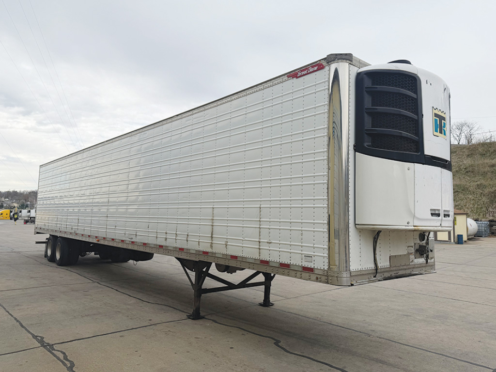 White Great Dane Everest SS refrigerated trailer with TR logo on front cooling unit, side blue stripe, undercarriage visible, parked on concrete.