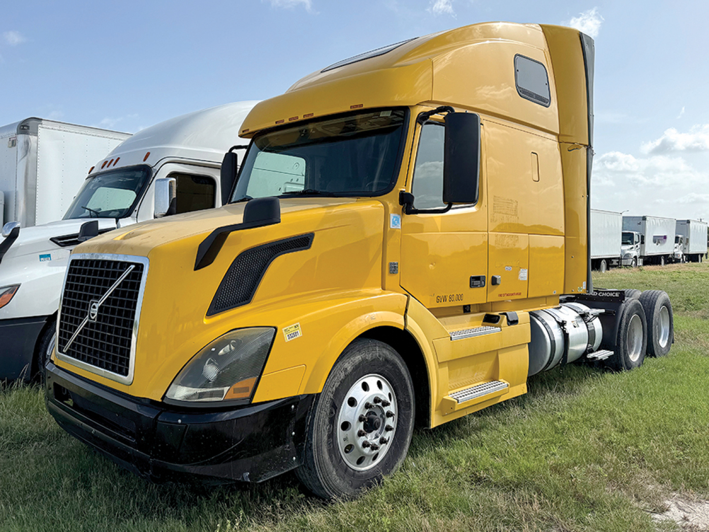 Volvo VNL 670 sleeper cab in yellow, front-left view, with fuel tanks and dual rear axles visible.
