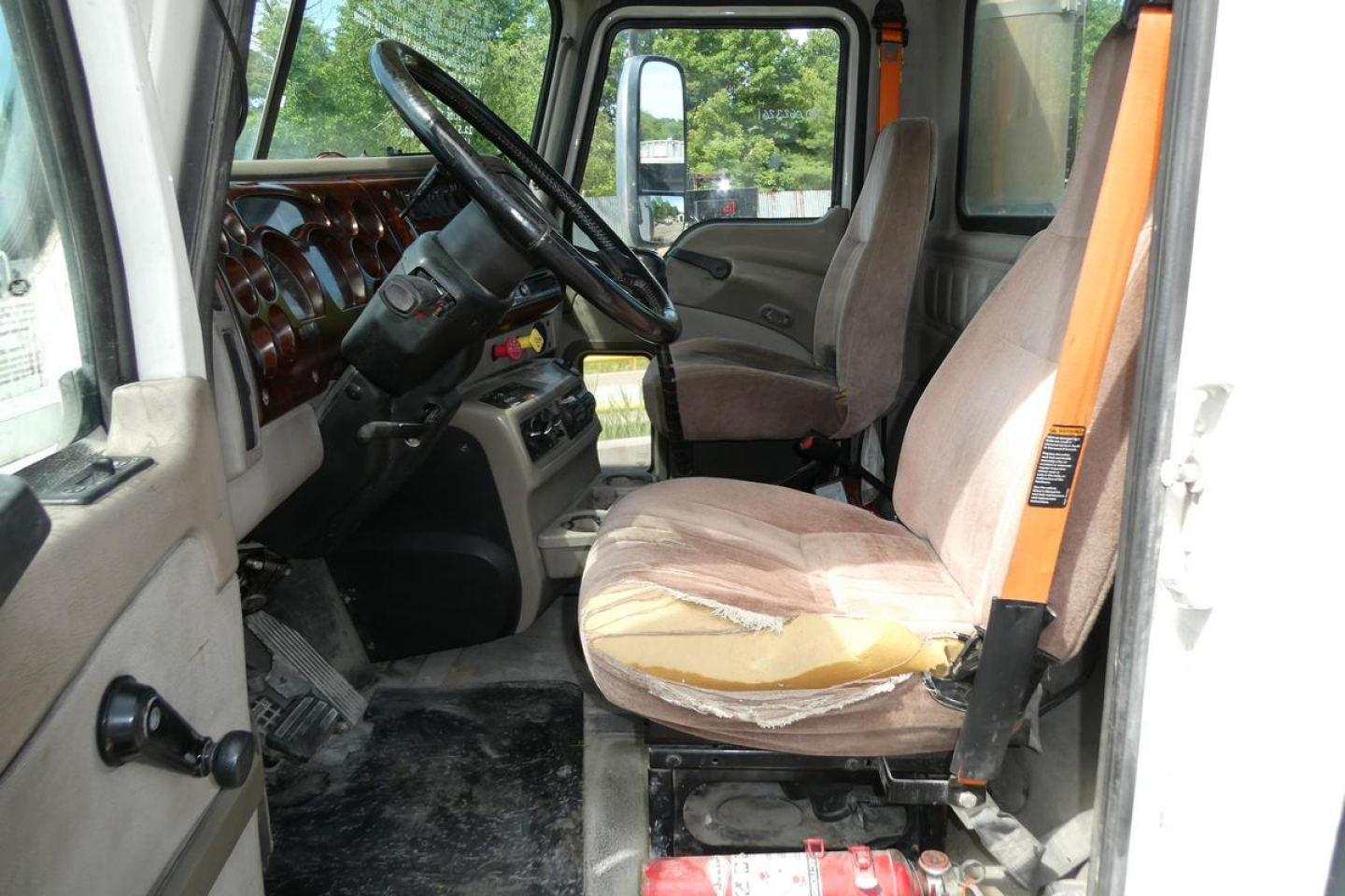 Cab interior of a 2007 Mack CXN613 daycab showing driver's seat and passenger seat, steering wheel, and dashboard.