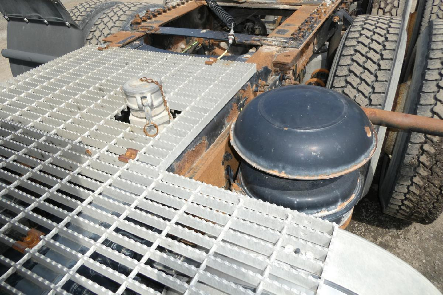 Gas tank and metal grid platform on a Mack CXN613 truck showing a round blue air tank and fuel line fittings.