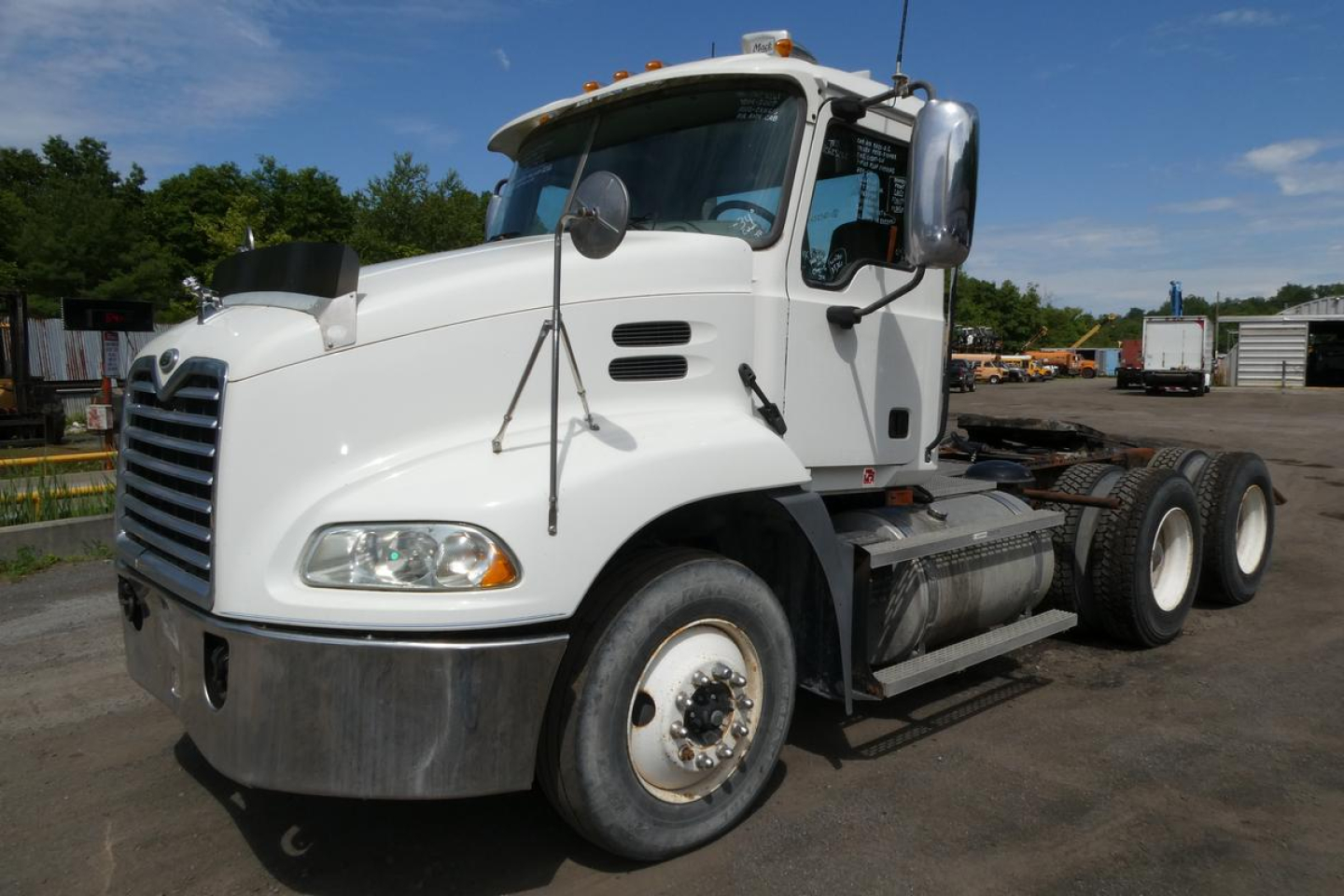 Truck cab and chassis showing Mack CXN613 series with white exterior, front grille, side mirrors, and dual rear axles.