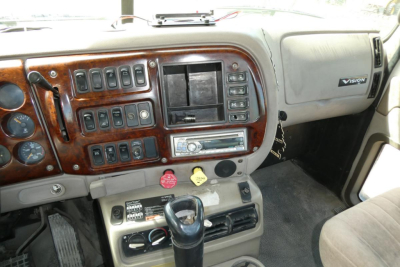 Dashboard and center console of a Mack CXN613 truck cab showing switches, ignition area, and gear shifter.