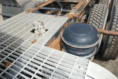 Gas tank and metal grid platform on a Mack CXN613 truck showing a round blue air tank and fuel line fittings.