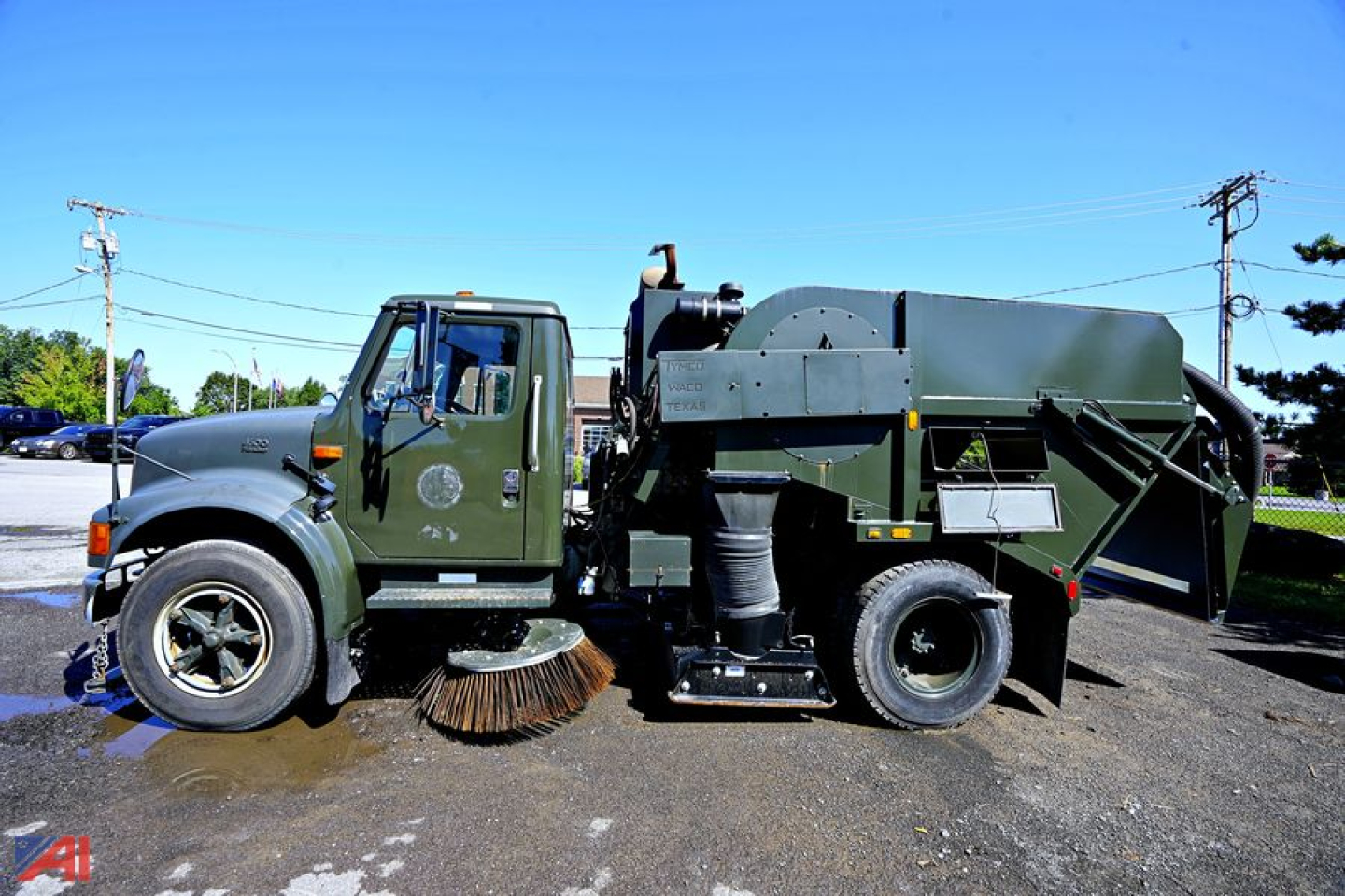 International 4600 sweeper truck side view showing large rear vacuum/sweeping equipment and rotating brush, green cab and chassis.