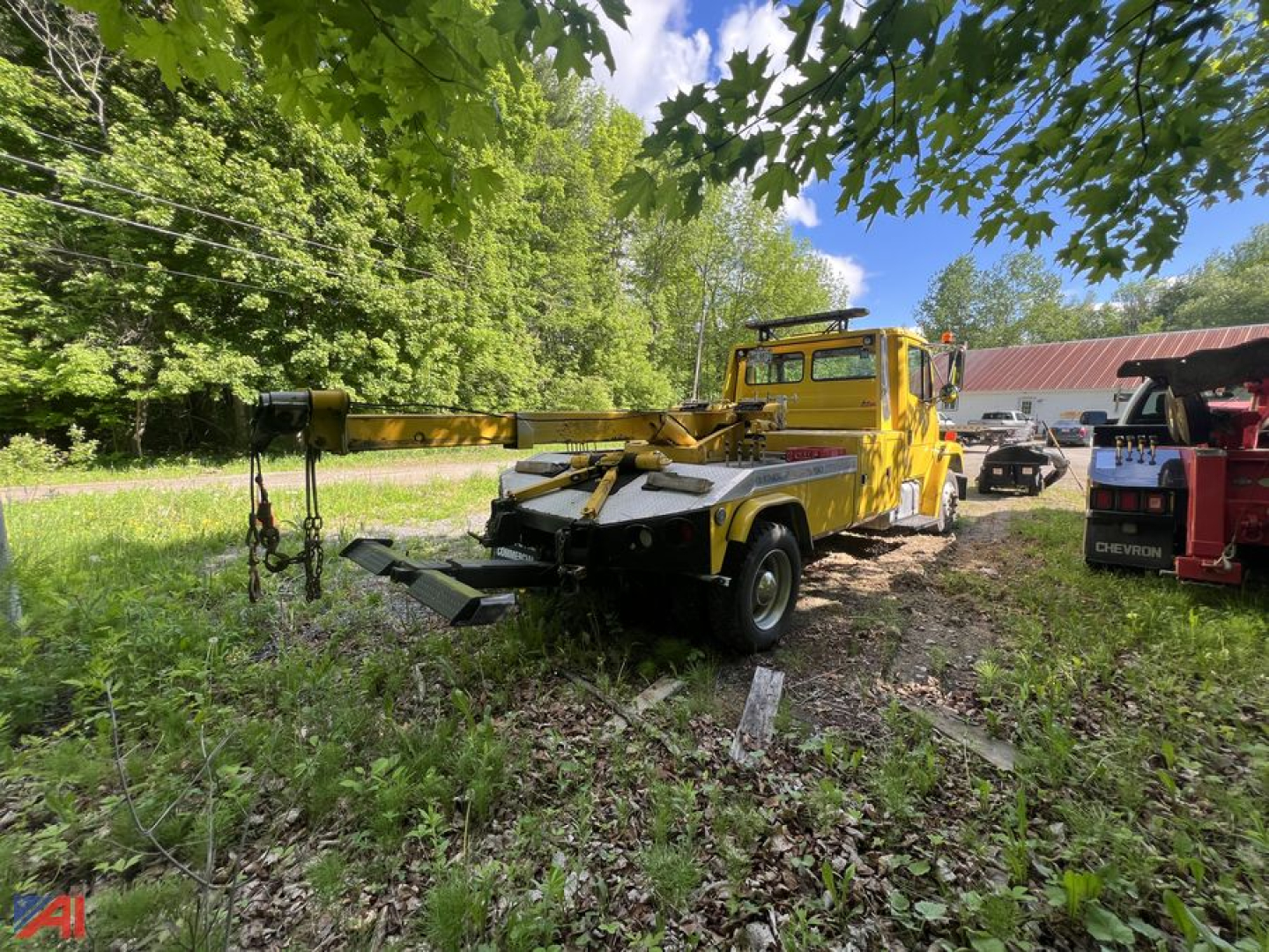 1998 Freightliner FL50 wrecker in a grassy lot, yellow tow truck with front wheel lift and boom, rear deck equipment visible.