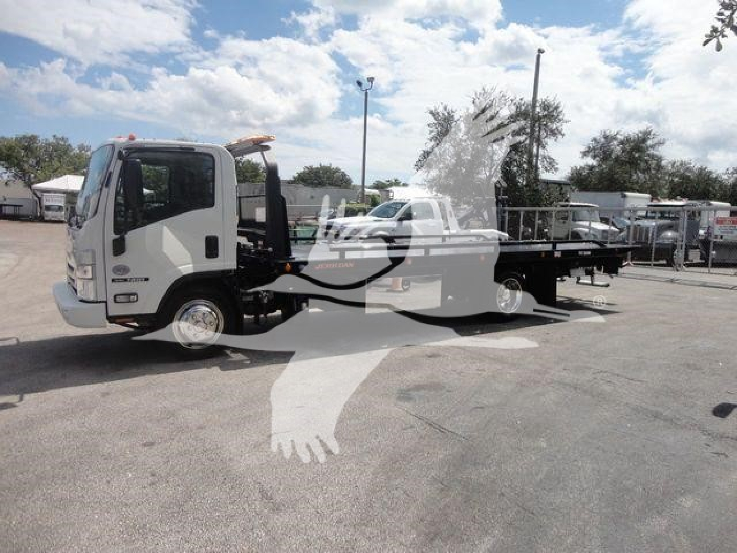 Isuzu NPR truck with rollback tow body, side view showing flatbed and cab, stock number NRRDSL22XLP.